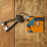 An orange, teal and grey key ring on a table. The key ring has a personalised message reading "thank you Mrs Brown, its been a hoot!" and an illustration of an owl. 