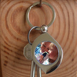 A metal keyring with a personalised photo in the centre. The keying is silver coloured metal and is in a teardrop shape. 