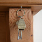 A personalised metal bottle opener keyring hanging on a hook with 2 keys